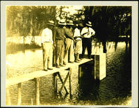 Men standing on wooden pier near outlet
