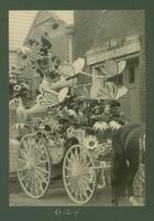 A firemen's parade float, perhpas the Washington Fire Company No. 1., featuring butterflies, flowers, and spider webs on the wheels.