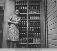 Woman with a cupboard full of canned goods in Bayou Sale Louisiana in 1944