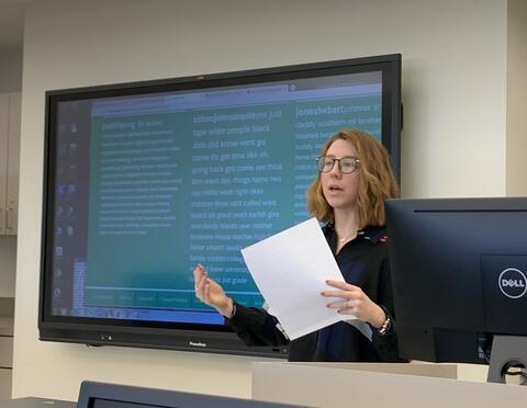 Image of a woman presenting in front of a screen displaying word frequency data. 
